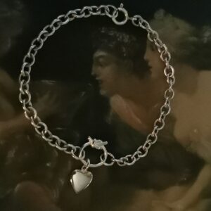 Sterling silver bracelet featuring a love knot connector in the middle with a small heart dangling from it